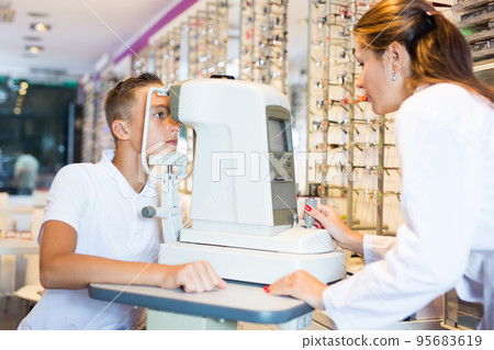 Female optometrist testing eyesight of boy Female optometrist testing eyesight of boy 95683619