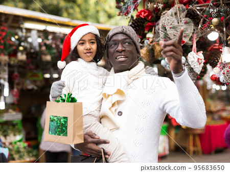 Man with small daughter looking around at Christmas fair Man with small daughter looking around at Christmas fair 95683650