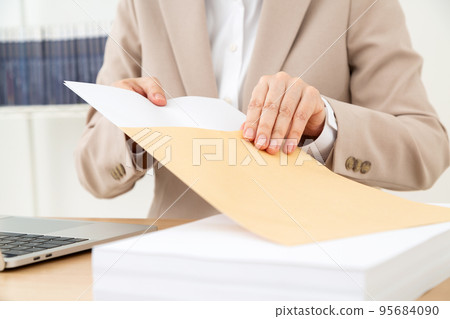 中層女商人在案頭工作中準備文件 95684090