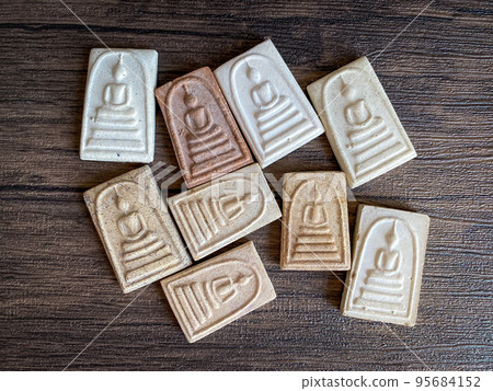 Thai buddha amulet isolated on wooden background. 95684152