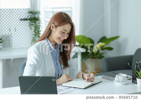 Portrait of a young businesswoman or business owner working with a notebook and tablet computer at office room. 95685710
