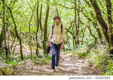 Man tourist climb barefoot the mountain to the Ostrog. It is a tradition to climb barefoot. Monastery of Ostrog, Serbian Orthodox Church situated against a vertical background, high up in the large 95687668