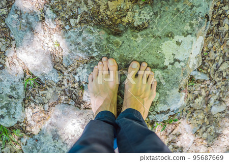 Man tourist climb barefoot the mountain to the Ostrog. It is a tradition to climb barefoot. Monastery of Ostrog, Serbian Orthodox Church situated against a vertical background, high up in the large 95687669