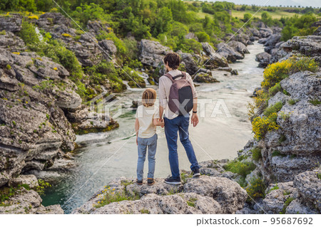 father and son tourists on background of Picturesque Niagara Falls on the river Cievna. Montenegro, near Podgorica. Travel around Montenegro concept 95687692