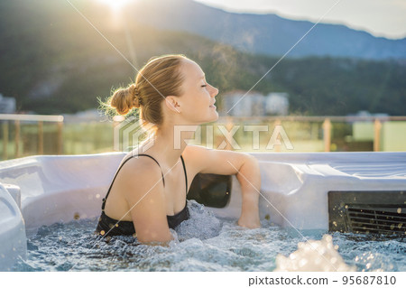 Portrait of young carefree happy smiling woman relaxing at hot tub during enjoying happy traveling moment vacation life against the background of green big mountains 95687810