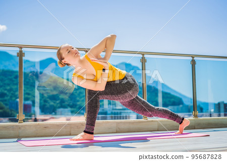 Beautiful woman doing yoga outdoors on a rooftop terrace Beautiful woman doing yoga outdoors on a rooftop terrace 95687828
