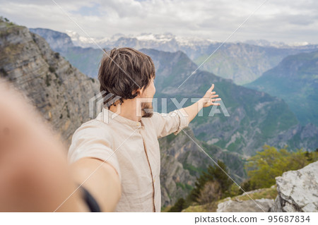 Man tourist on background of Breathtaking panoramic view of the Grlo Sokolovo gorge in Montenegro. In the foreground is a mountain, the flat side of which forms a cliff, and the ridge is overgrown 95687834