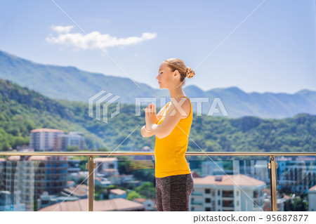 Beautiful woman doing yoga outdoors on a rooftop terrace Beautiful woman doing yoga outdoors on a rooftop terrace 95687877