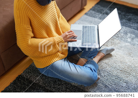 Portrait of a young Asian woman using a computer on the sofa. 95688741