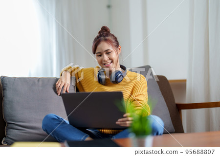 Portrait of a young Asian woman using a computer on the sofa. Portrait of a young Asian woman using a computer on the sofa. 95688807