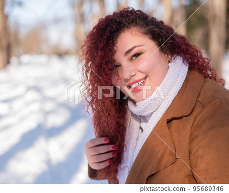 Portrait of a red-haired curly fat woman in the park in winter.  95689346