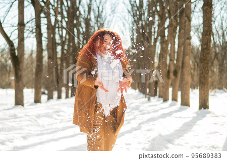 Fat caucasian woman playing snowballs in the park.  95689383