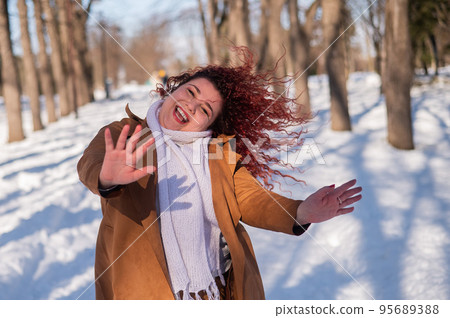 Fat caucasian woman dancing on a walk in the park in winter. Fat caucasian woman dancing on a walk in the park in winter. 95689388