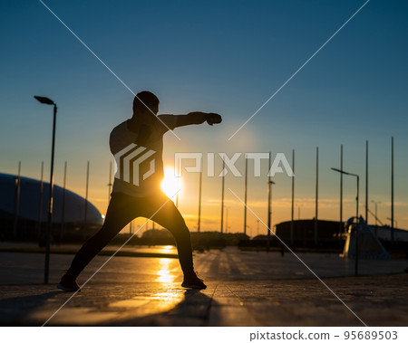 A man trains boxing at sunset outdoors. A man trains boxing at sunset outdoors. 95689503