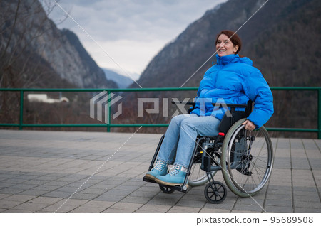 A woman in a wheelchair on a point view admires the high mountains. Thrust to life. A woman in a wheelchair on a point view admires the high mountains. Thrust to life. 95689508
