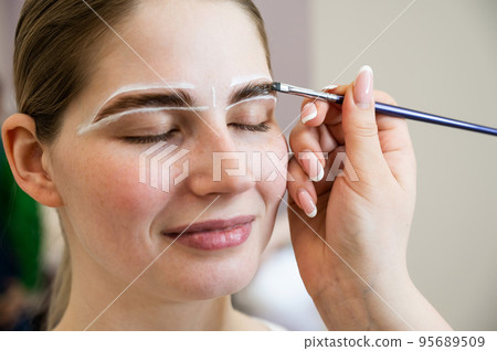 The master draws the shape of the eyebrows with white paint before coloring.  95689509