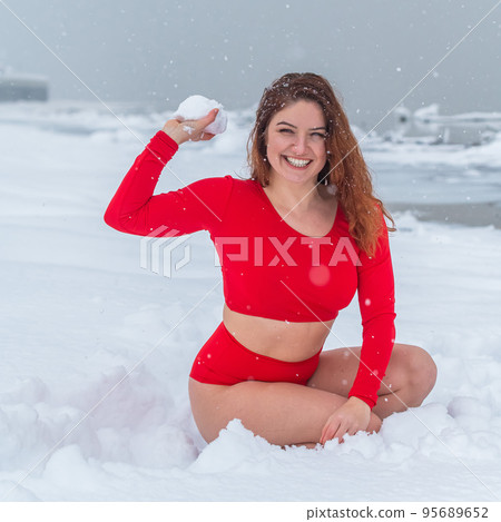 Caucasian woman in a red tracksuit plays snowballs. Caucasian woman in a red tracksuit plays snowballs. 95689652