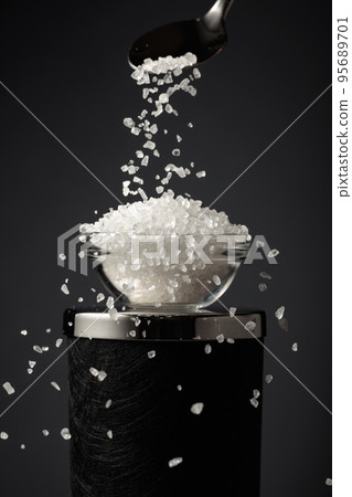 Sea salt is poured into a small bowl. 95689701