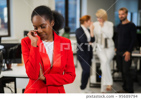 Young african woman crying because of the ridicule of colleagues. Racial discrimination in the office. Young african woman crying because of the ridicule of colleagues. Racial discrimination in the office. 95689794