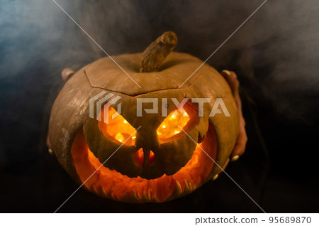 The witch is holding a pumpkin jack about a lantern glowing in the dark. Halloween. The witch is holding a pumpkin jack about a lantern glowing in the dark. Halloween. 95689870