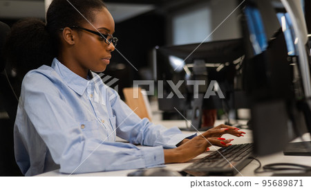 African young woman typing on a computer at her desk in the office. African young woman typing on a computer at her desk in the office. 95689871