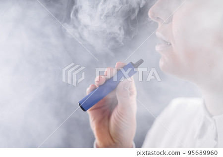 Caucasian woman smokes a disposable vape in the studio. Caucasian woman smokes a disposable vape in the studio. 95689960