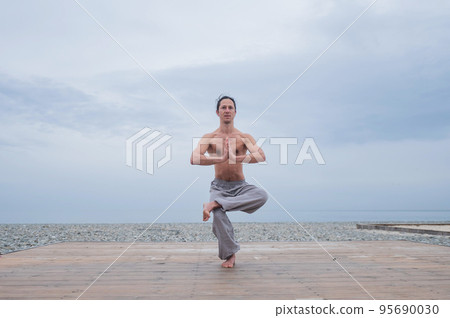 Caucasian man practices martial arts outdoors. balance and meditation. Caucasian man practices martial arts outdoors. balance and meditation. 95690030