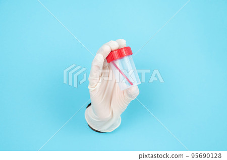 A woman's hand in a rubber glove sticks out through a blue paper background and holds a container for collecting feces. A woman's hand in a rubber glove sticks out through a blue paper background and holds a container for collecting feces. 95690128