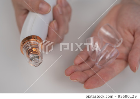 Woman holding a vacuum pore cleaner with different nozzles. Woman holding a vacuum pore cleaner with different nozzles. 95690129