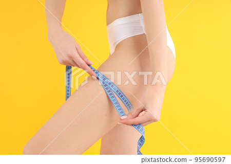 Concept of weight loss with thin girl on yellow background Concept of weight loss with thin girl on yellow background 95690597