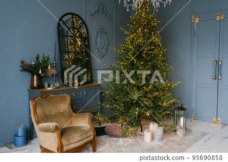 Christmas and New Year decorate the dark interior of the room. A festively decorated room with a fireplace, an armchair and a mirror. Festive Christmas night with lights on the Christmas tree with 95690858