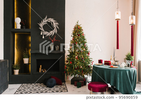 Stylish luxurious interior of the dining room with a Christmas tree. A chair near a round table and a fireplace. Classic modern house 95690859