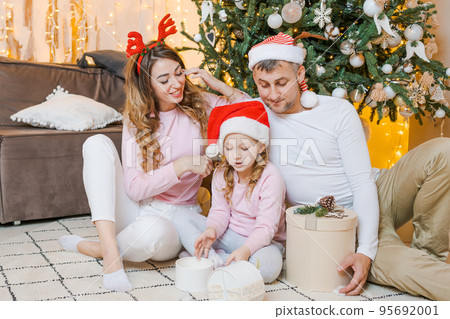 Christmas family. Happy portrait dad, mom and daughter in santa hats sitting 95692001