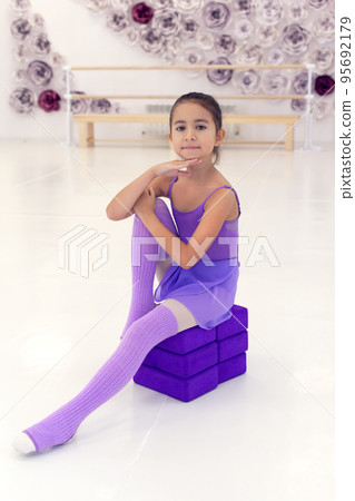 Beautiful little ballerina standing on her toes and training in dance hall. 95692179