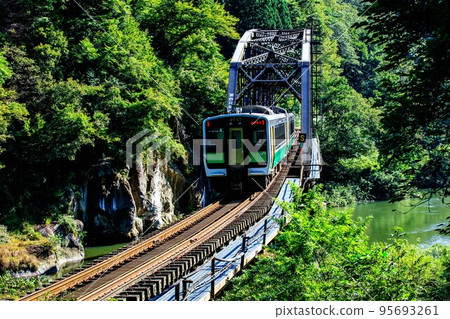 Tadami Line Kiha E120 type train crossing the No. 4 Tadami River Bridge in early autumn (Kanayama Town, Fukushima Prefecture, September) 95693261
