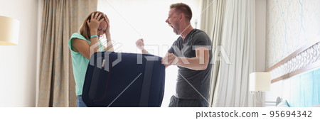 Woman in stress, husband scream and pack stuff in suitcase for work trip, couple fight 95694342