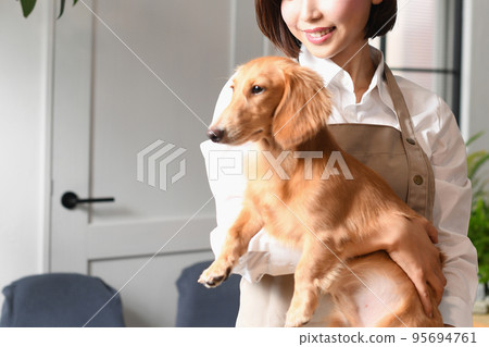 A trimmer woman holding a dog (pet) A trimmer woman holding a dog (pet) 95694761