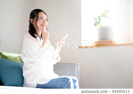 一個可愛的女人拿著智能手機，帶著可愛的微笑 95695011