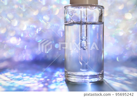 A bottle of serum with a pipette in tinsel in a Christmas theme in purple shades. A bottle of serum with a pipette in tinsel in a Christmas theme in purple shades. 95695242
