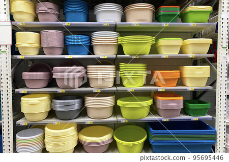 Shopping with background of colorful plastic baskets, bowls and basins on shelf. Inexpensive alternative to dishes made from natural materials. 95695446