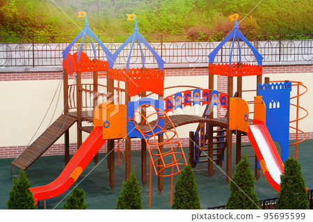 Colorful playground on yard in city. Children playground surrounded by green trees in sunlight in summer. Colorful playground on yard in city. Children playground surrounded by green trees in sunlight in summer. 95695599