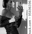 Mobile photo of a young woman with a glass of champagne 95696396
