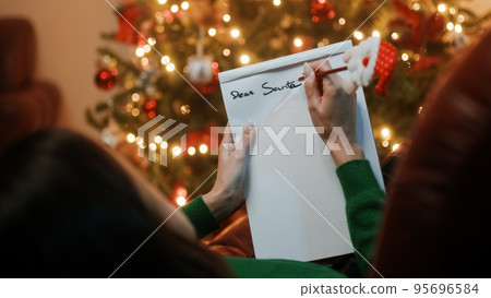Girl writes christmas letter on the sofa 95696584