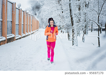 Gear Up for Cold Weather Running, How to Dress for Winter Running. Running woman in sportswear jogging in winter park. Fitness woman running during winter workout. Gear Up for Cold Weather Running, How to Dress for Winter Running. Running woman in sportswear jogging in winter park. Fitness woman running during winter workout. 95697170