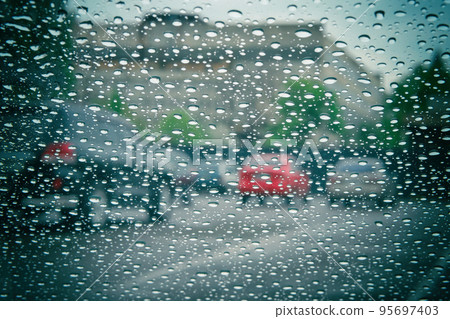 Road view through car window with rain drops. Car window on a rainy day. Highway view, background is out of focus. 95697403