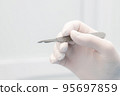 scalpel in the surgeon's hand close-up. a sterile glove on the hand. start of operation 95697859