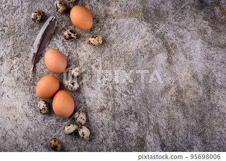Chicken and quail raw eggs on stone background Chicken and quail raw eggs on stone background 95698006
