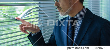 Detective senior man looking through blinds 95698780