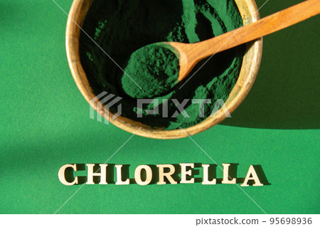 Blue-green algae with message CHLORELLA and spirulina powder in bamboo eco bowl. Super powder in spoon. Detox superfood. Natural supplement of algae Blue-green algae with message CHLORELLA and spirulina powder in bamboo eco bowl. Super powder in spoon. Detox superfood. Natural supplement of algae 95698936