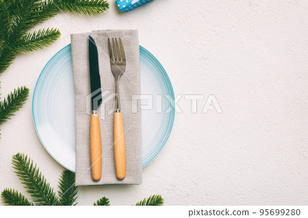 Christmas table place setting with christmas decor and plates, kine, fork and spoon. Christmas holiday background. Top view with copy space Christmas table place setting with christmas decor and plates, kine, fork and spoon. Christmas holiday background. Top view with copy space 95699280
